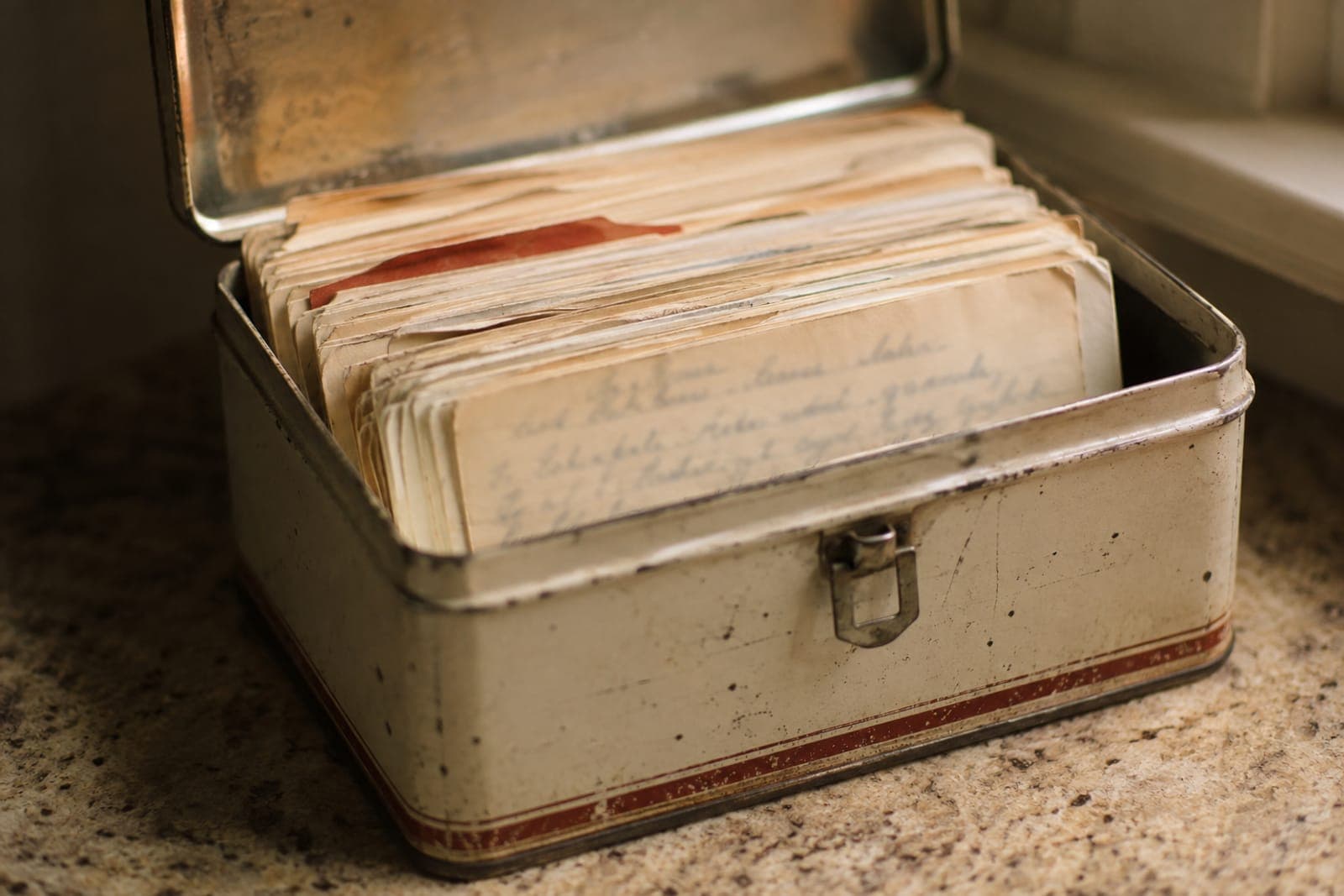 An old tin box full of worn, handwritten recipe cards